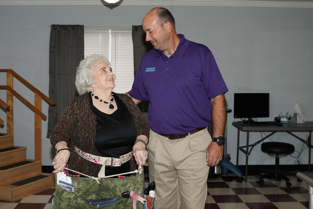 An older woman smiling while talking to a Brook Stone Living Center staff member