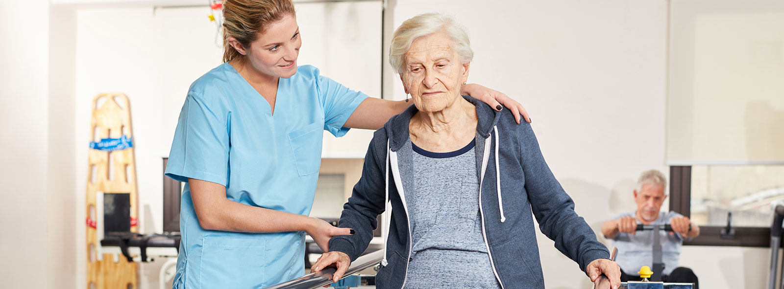 Rehabilitation therapist supports senior woman on treadmill in physiotherapy.